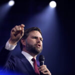 JD Vance speaking on stage at an event.